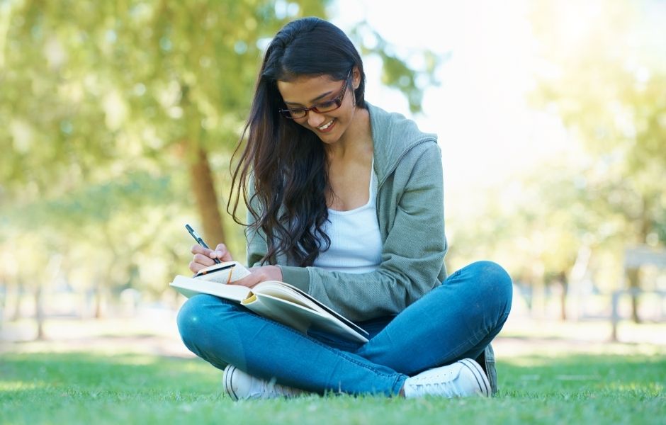 étudiante qui travaille sereinement dans l'herbe